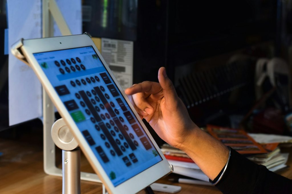 Employee hand using POS point of sale system on digital tablet looking at restaurant floor plan